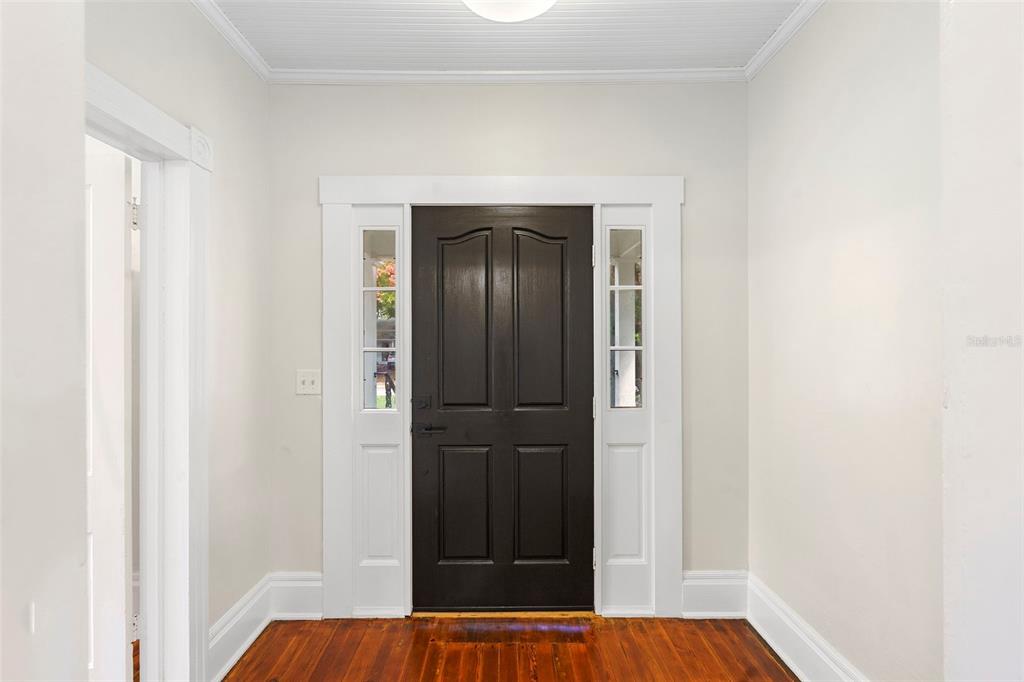A foyer features a dark front door with sidelights, white trim, and hardwood flooring — 210 W UNIVERSITY AVENUE, DELAND, FL