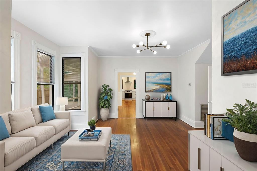 A living room features hardwood floors, a beige sofa, a central chandelier, and a doorway — 210 W UNIVERSITY AVENUE, DELAND, FL