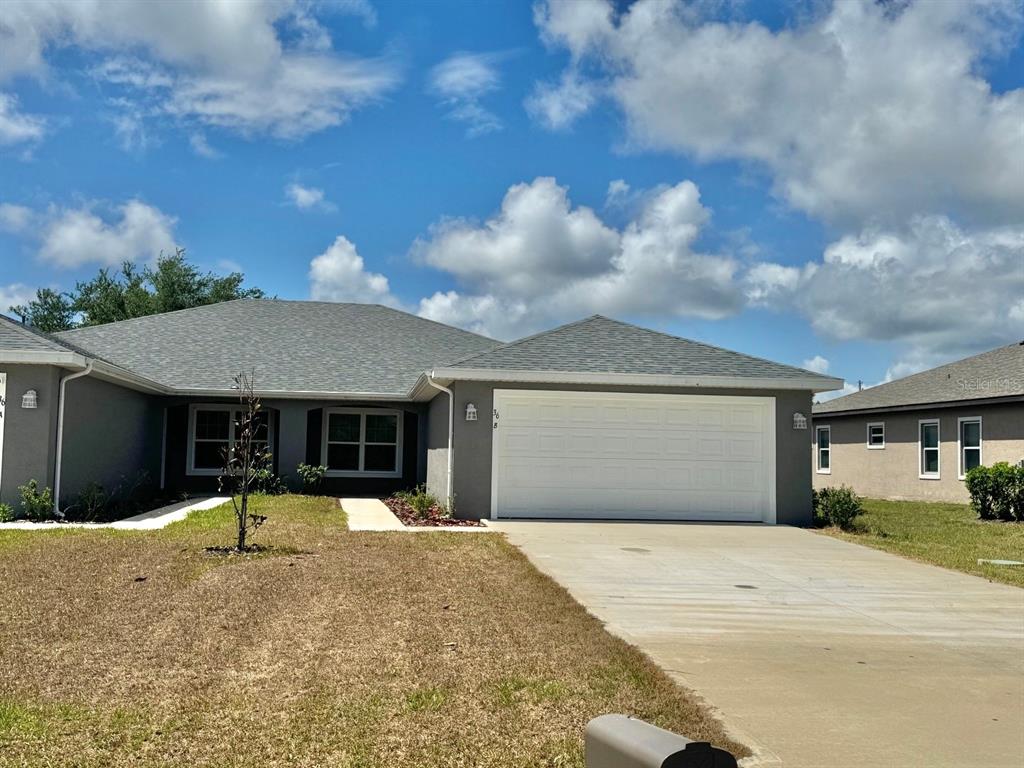 A gray single-story house with a white garage door and a concrete driveway — 36 LOUISBURG LANE UNIT A & B, PALM COAST, FL