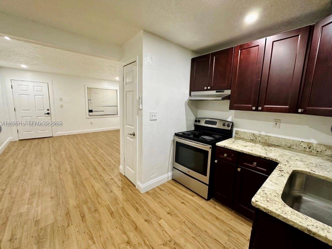 A kitchen with dark wood cabinets and granite countertops opens into a living area — 813 W Jefferson ST # 5, Orlando FL 32805, ORLANDO, FL