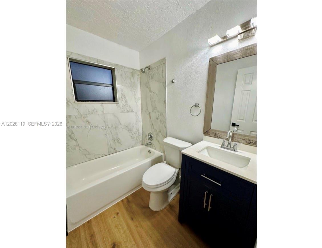 A bathroom features a white bathtub with marble-style tile walls, a toilet, and a vanity — 813 W Jefferson ST # 5, Orlando FL 32805, ORLANDO, FL