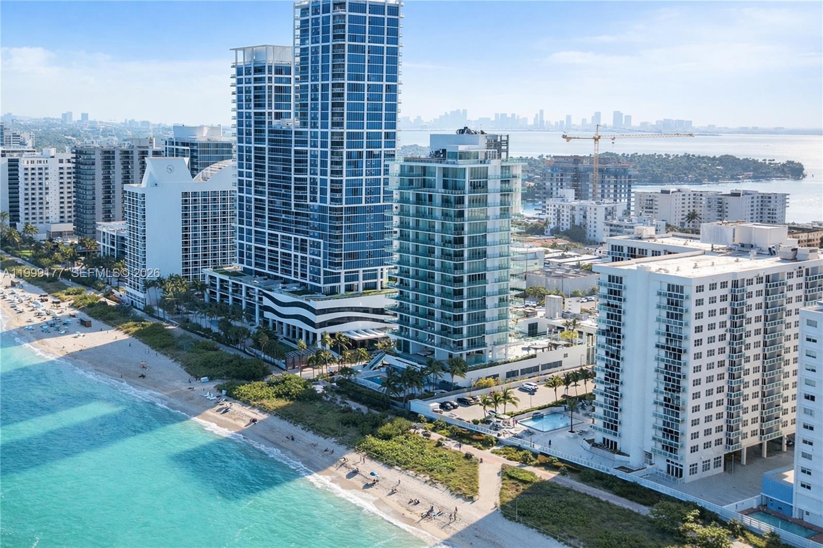 An aerial view shows several high-rise residential buildings situated along a sandy beach and ocean — 6917 Collins Ave # 1611, Miami Beach FL 33141, MIAMI BEACH, FL