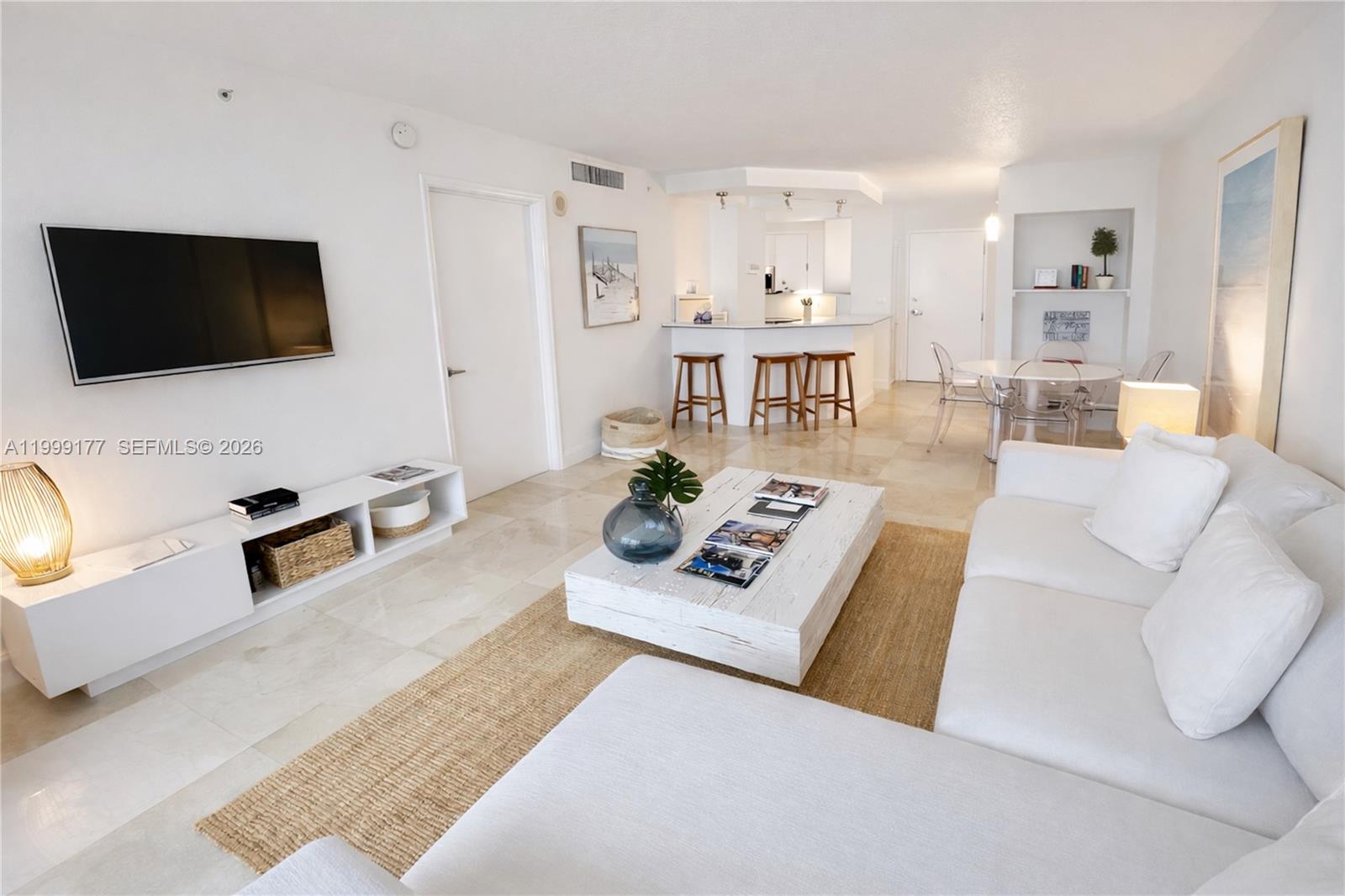 A bright living room features white furniture, a wooden coffee table, and a kitchen bar — 6917 Collins Ave # 1611, Miami Beach FL 33141, MIAMI BEACH, FL