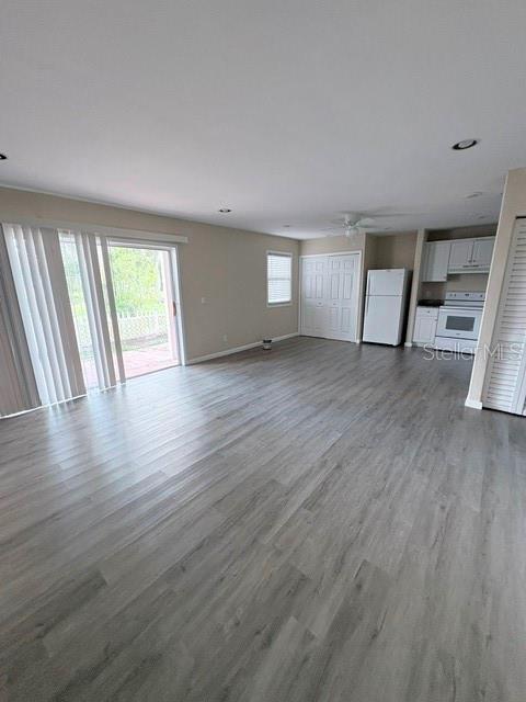An open-concept living area features gray wood-look flooring, recessed lighting, and an adjacent kitchen — 13756 ORANGE SUNSET DRIVE UNIT 101, TAMPA, FL