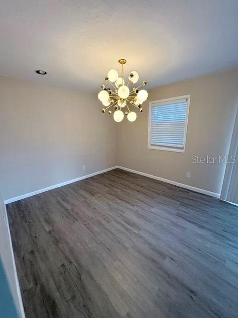 An empty room features light gray walls, wood-look flooring, and a modern gold sputnik chandelier — 13756 ORANGE SUNSET DRIVE UNIT 101, TAMPA, FL