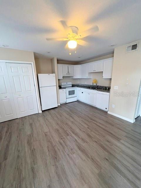 A kitchen with white cabinets, white appliances, and light wood-look flooring — 13756 ORANGE SUNSET DRIVE UNIT 101, TAMPA, FL