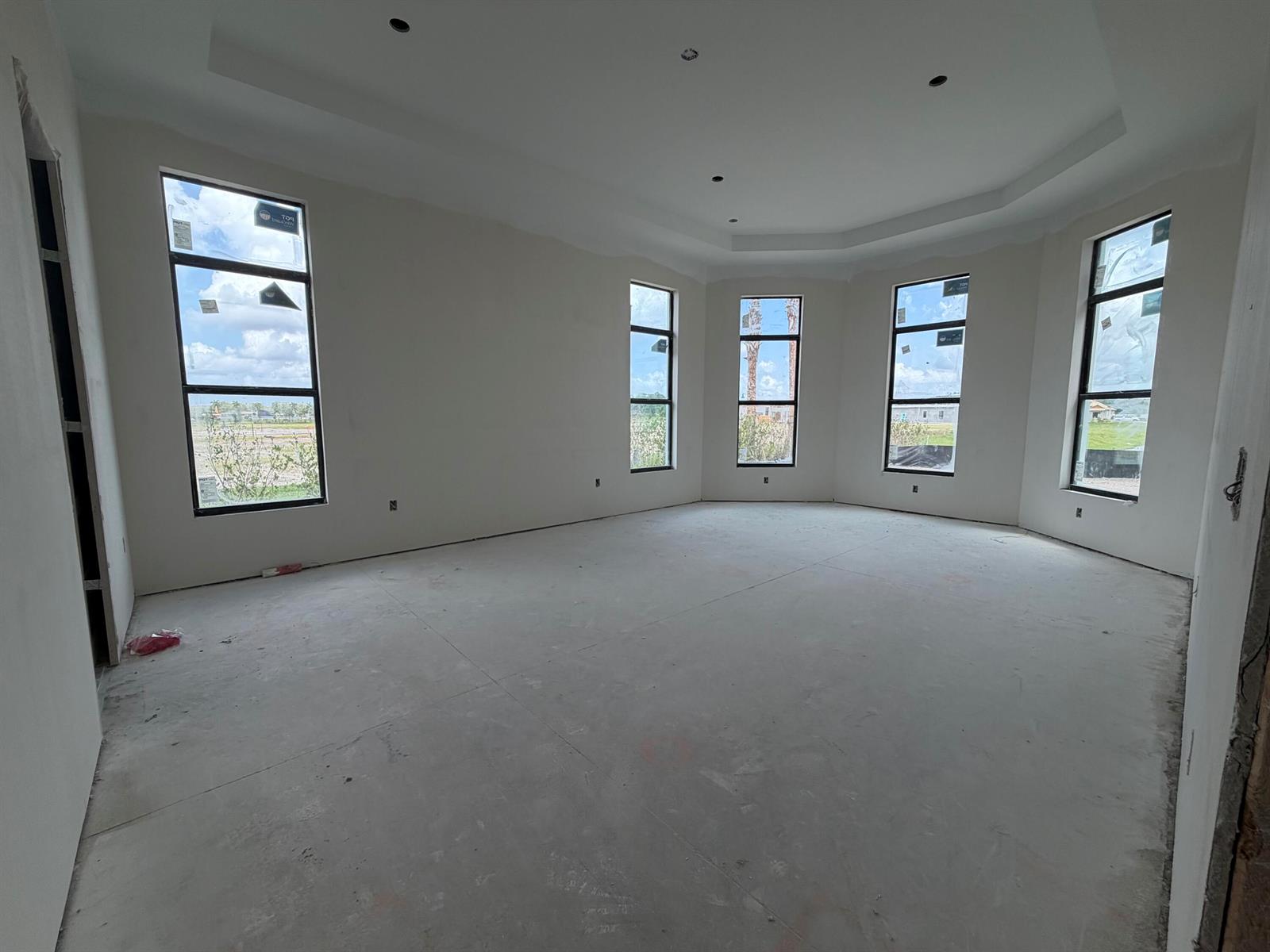 An unfinished room with a tray ceiling, concrete floors, and five tall windows — 10180 Amara Ranch Drive, Lake Worth FL 33449, LAKE WORTH, FL