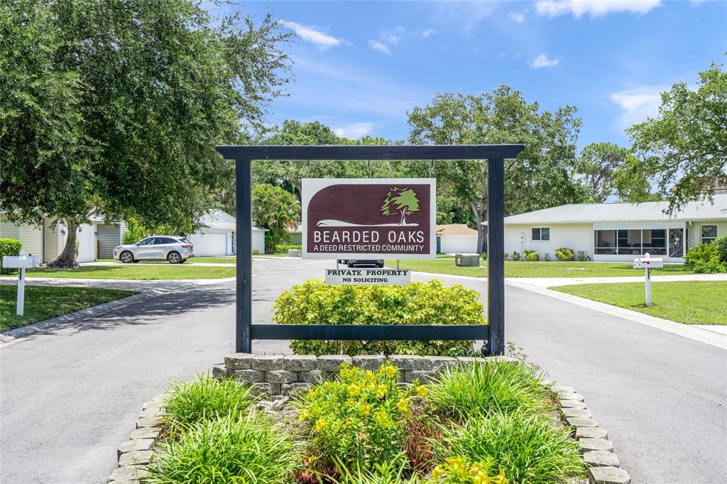 A sign for Bearded Oaks community stands in front of a residential street with houses — 319 BEARDED OAKS CIRCLE, SARASOTA, FL