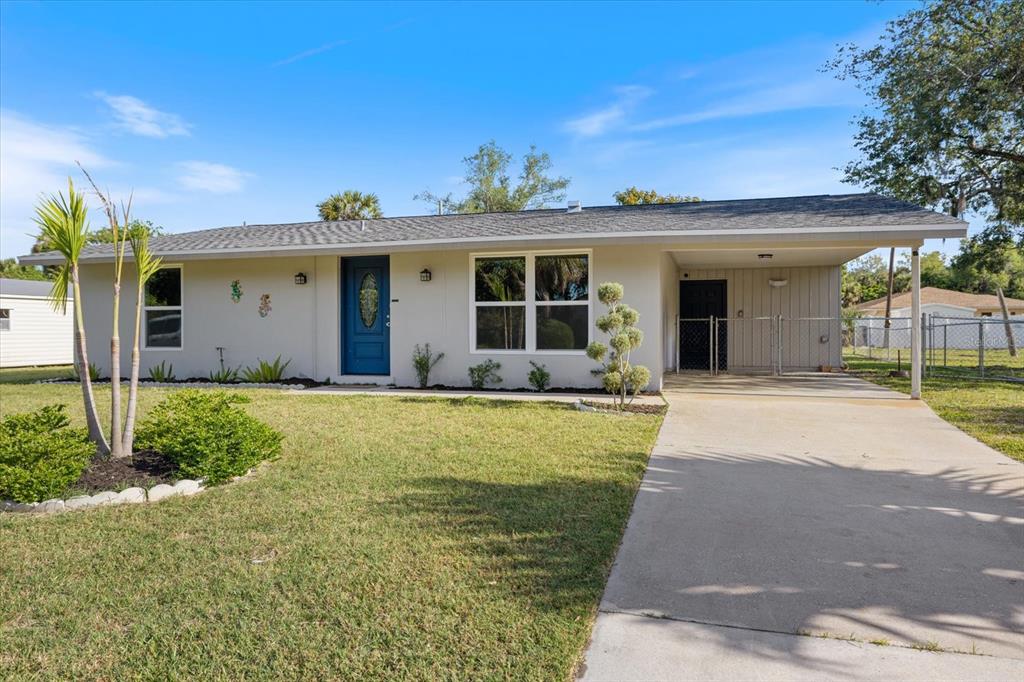 A single-story house with a blue front door, a concrete driveway, and an attached carport — 1184 BARBOUR AVENUE, PORT CHARLOTTE, FL