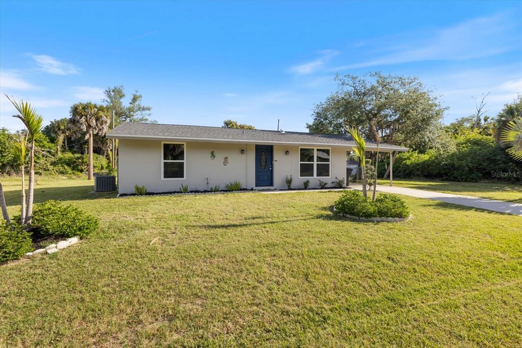 A single-story house with a light-colored exterior, a blue front door, and a carport — 1184 BARBOUR AVENUE, PORT CHARLOTTE, FL