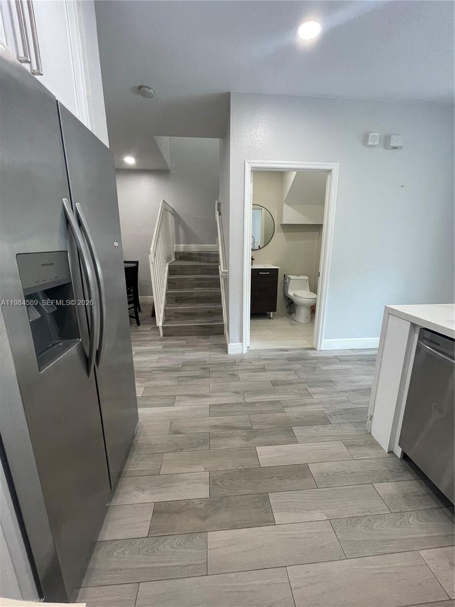 A kitchen view shows a stainless steel refrigerator, wood-look tile flooring, stairs, and a bathroom — 8900 SW 226th Ter, Cutler Bay FL 33190, CUTLER BAY, FL