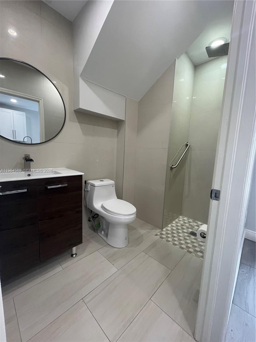 A modern bathroom features a dark wood vanity, a white toilet, and a tiled shower — 8900 SW 226th Ter, Cutler Bay FL 33190, CUTLER BAY, FL