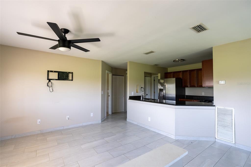 A living room with tile flooring and a ceiling fan opens to a kitchen area — 5203 WATERVIEW WAY UNIT 5203, WINTER HAVEN, FL