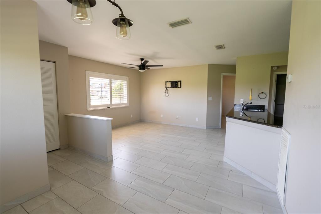 An open-concept living area features light tile flooring, a ceiling fan, and a kitchen pass-through — 5203 WATERVIEW WAY UNIT 5203, WINTER HAVEN, FL