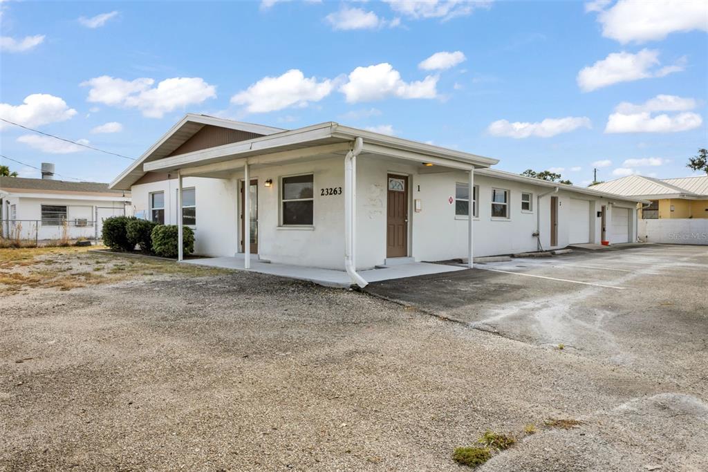 A single-story white building with a covered porch and gravel parking area — 23263 HARBORVIEW RD, PORT CHARLOTTE, FL