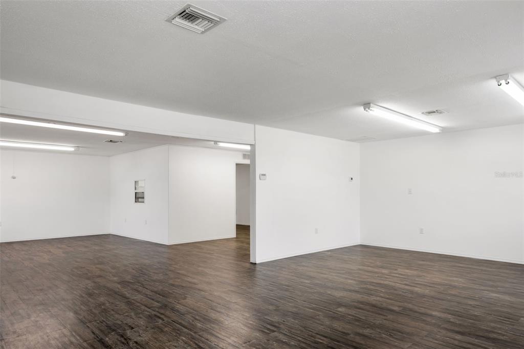 An empty room features white walls, recessed lighting, and dark wood-look flooring — 23263 HARBORVIEW RD, PORT CHARLOTTE, FL