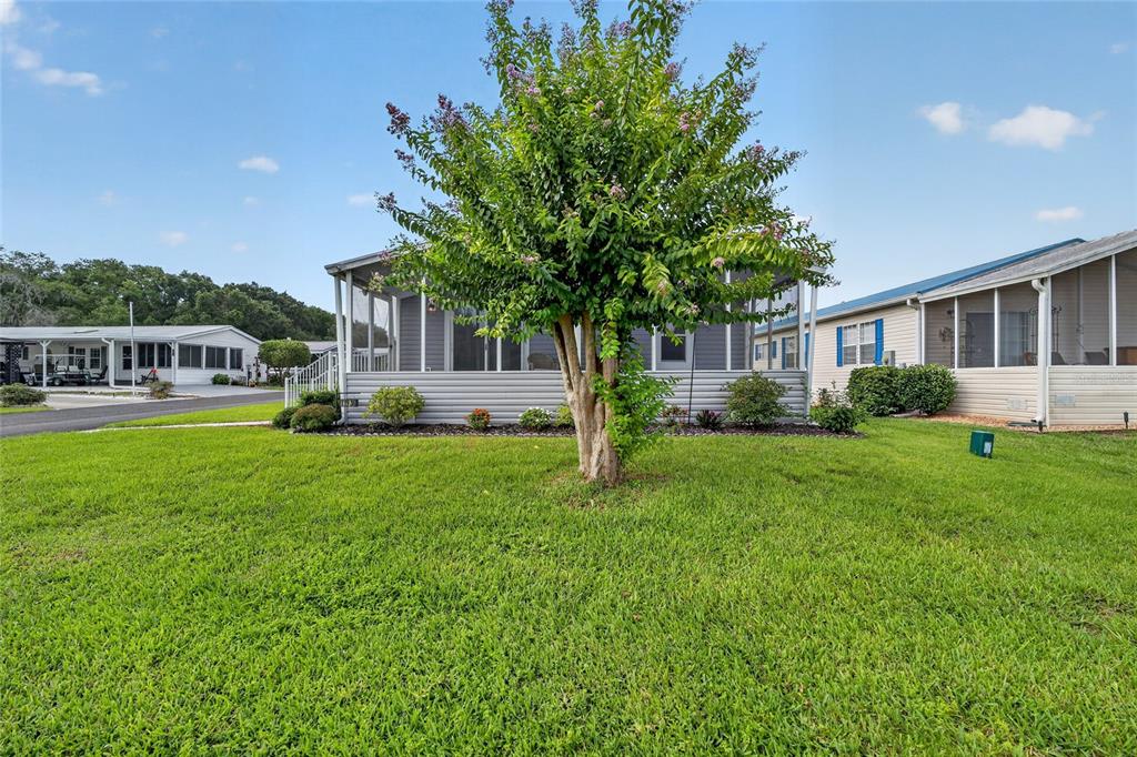 A single-story manufactured home with a screened porch and a large tree in the yard — 11936 STANWOOD WAY, LEESBURG, FL