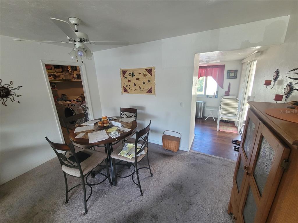 A dining area with a round table, chairs, carpeted flooring, and an adjacent laundry room — 22481 WESTCHESTER BOULEVARD UNIT B40, PUNTA GORDA, FL