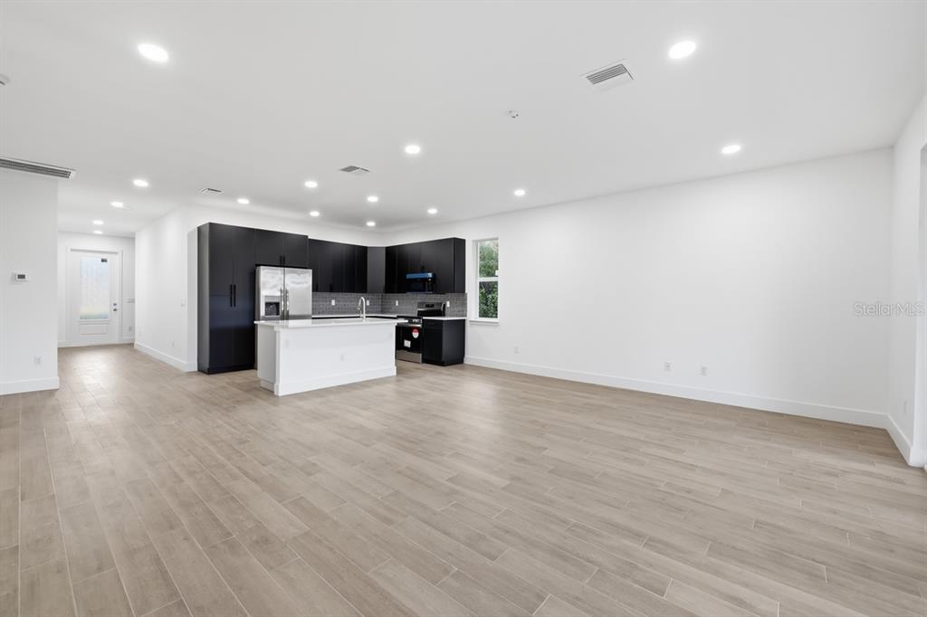 A modern kitchen with black cabinetry and a white island opens to a spacious room — 500 SUNSET ROAD N, ROTONDA WEST, FL