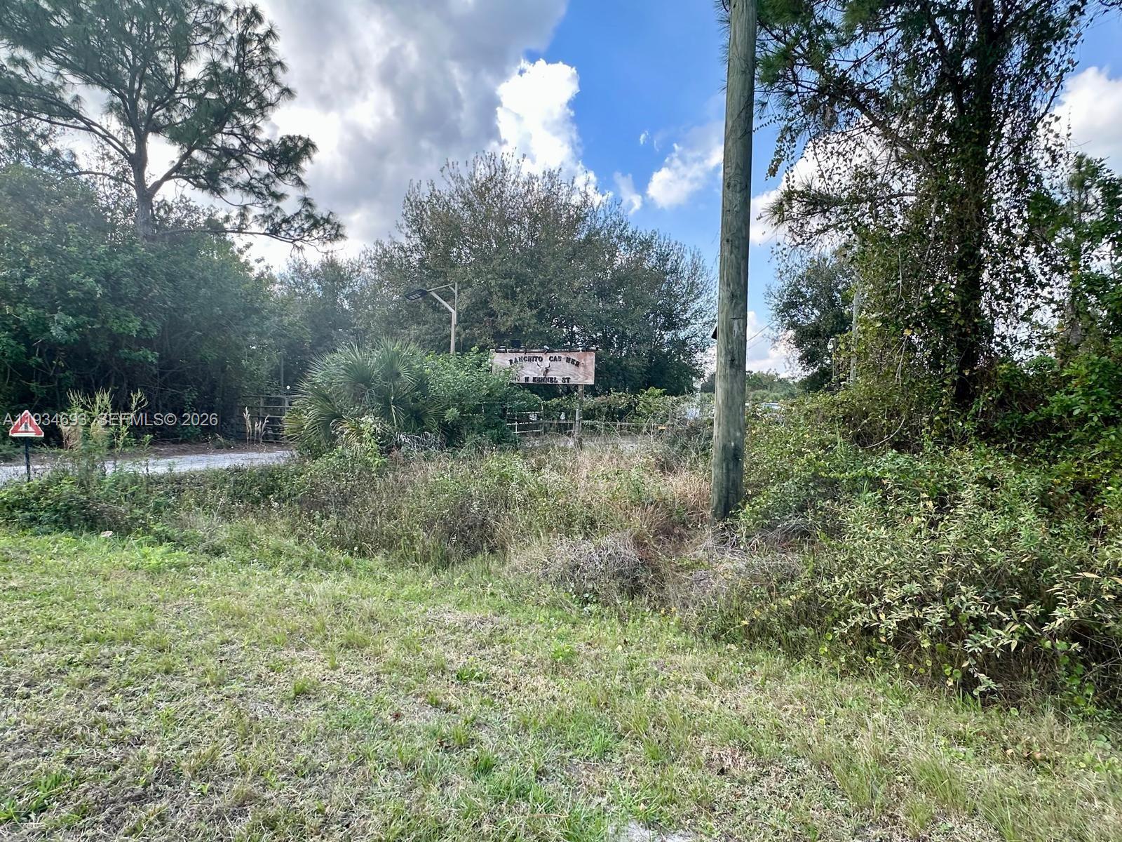 A dirt road leads to a gated entrance with a sign among trees and brush — 650 N Kennel, Clewiston FL 33440, CLEWISTON, FL