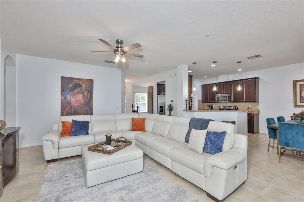 A living room features a white sectional sofa, an ottoman, and an open-concept kitchen — 823 SEMINOLE SKY DRIVE, RUSKIN, FL