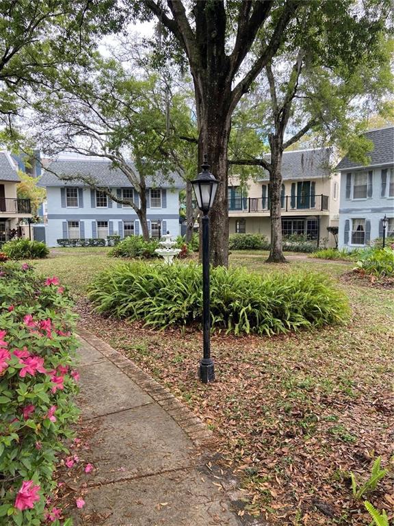 A paved walkway leads past a lamp post toward light blue multi-story residential buildings — 14405 BURGUNDY SQUARE, TAMPA, FL