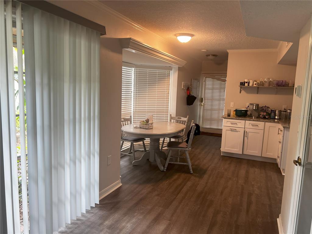 A dining area with a round table and chairs sits adjacent to a white kitchen — 14405 BURGUNDY SQUARE, TAMPA, FL
