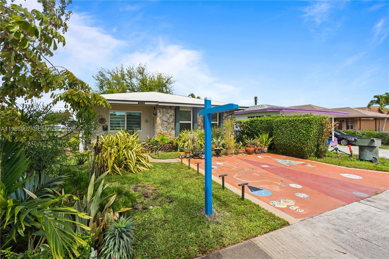 A single-story house features a stone facade, a painted driveway, and a blue signpost — 720 NW 4th St, Hallandale Beach FL 33009, HALLANDALE BEACH, FL