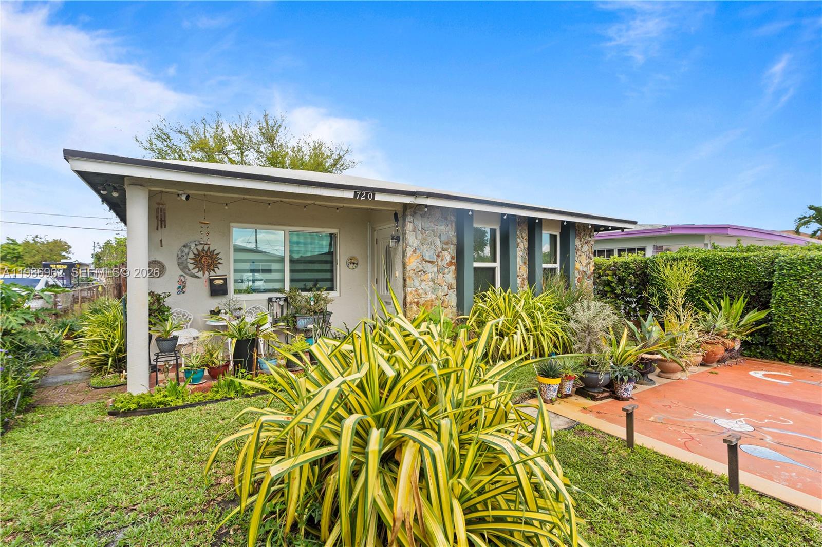 A single-story house features a stone facade, a covered porch, and a landscaped front yard — 720 NW 4th St, Hallandale Beach FL 33009, HALLANDALE BEACH, FL