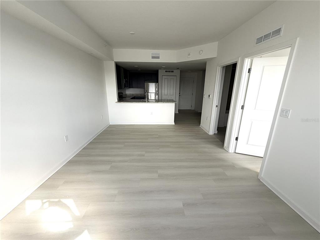 An open-concept living area features light wood-look flooring and a kitchen with dark cabinetry — 5587 MILLENIA PARK BLVD UNIT 303, ORLANDO, FL