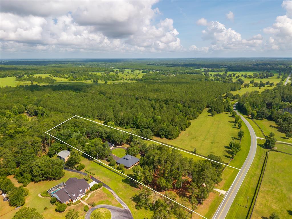 An aerial view shows a residential property outlined in white, surrounded by trees and fields — 6450 NW HIGHWAY 225, OCALA, FL