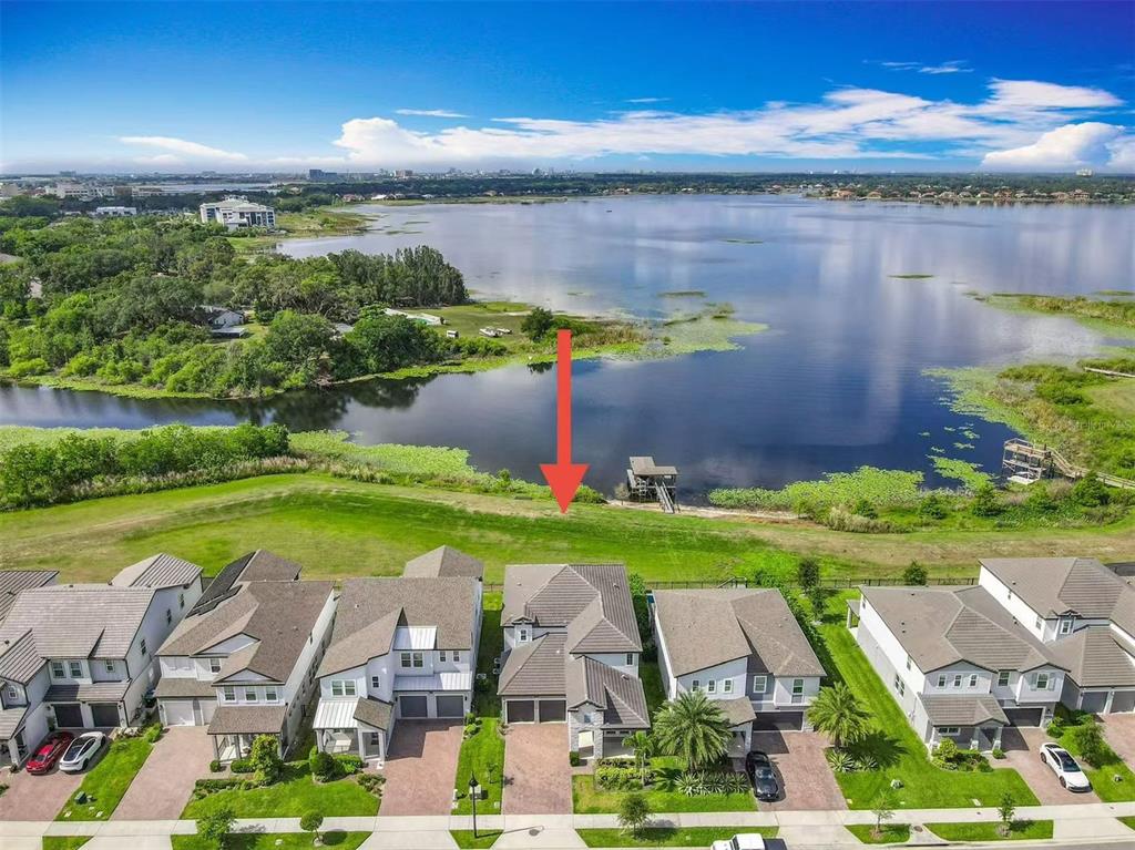 An aerial view shows a suburban house with a backyard overlooking a large lake — 7398 ALPINE BUTTERFLY LN, ORLANDO, FL