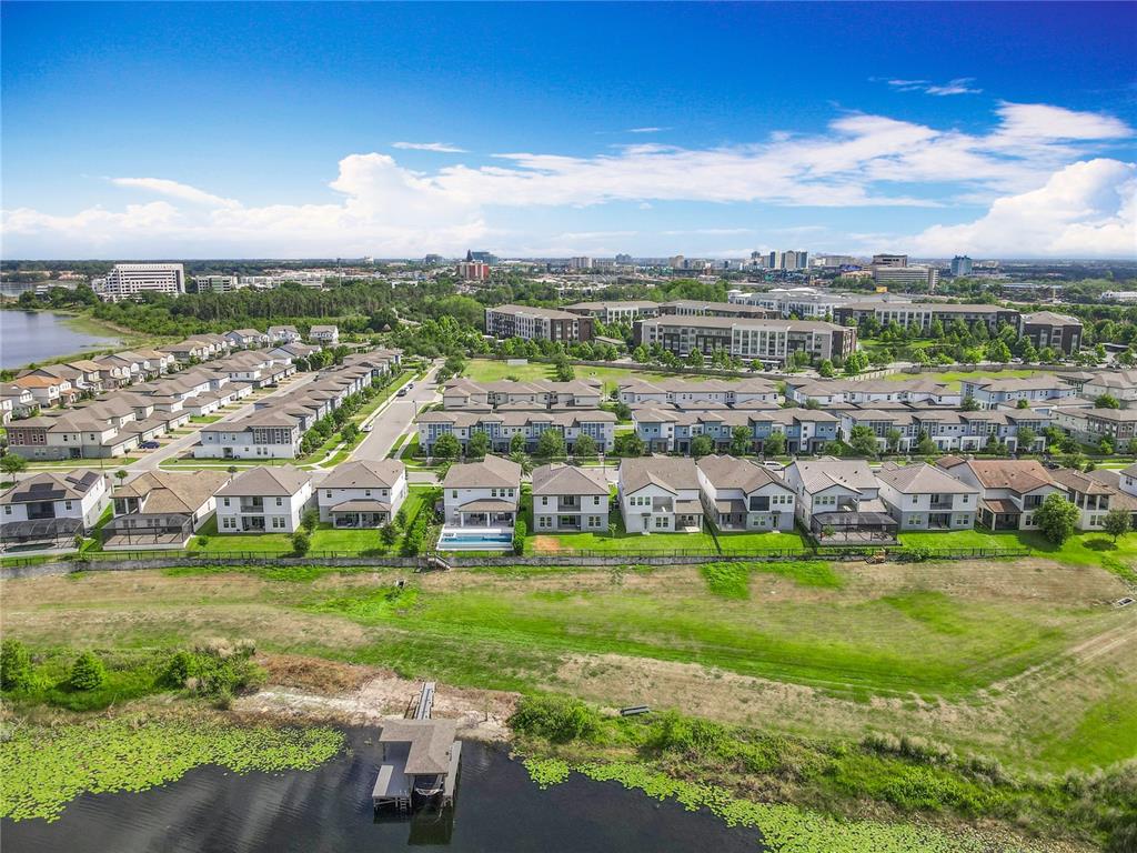 An aerial view shows a suburban neighborhood with houses, a lake, and a boat dock — 7398 ALPINE BUTTERFLY LN, ORLANDO, FL