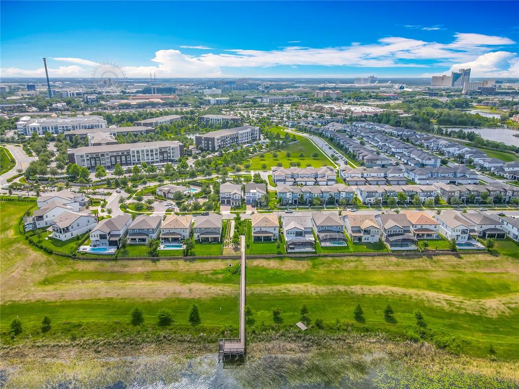 An aerial view shows a suburban neighborhood with houses, a wooden pier, and a lake — 7398 ALPINE BUTTERFLY LN, ORLANDO, FL