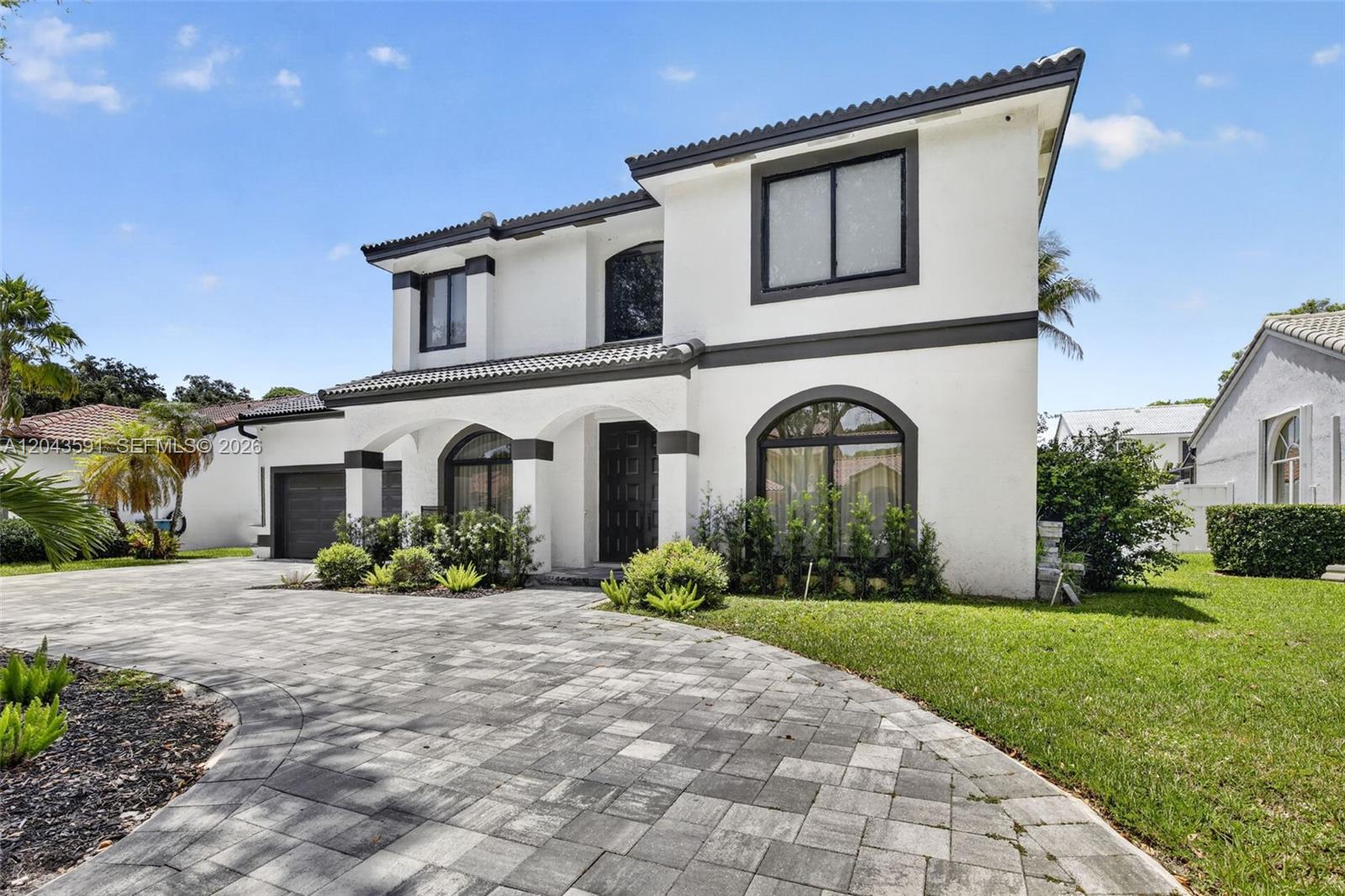 A two-story white house with dark trim features an arched entryway and paved driveway — 10746 Charleston Pl, Cooper City FL 33026, COOPER CITY, FL