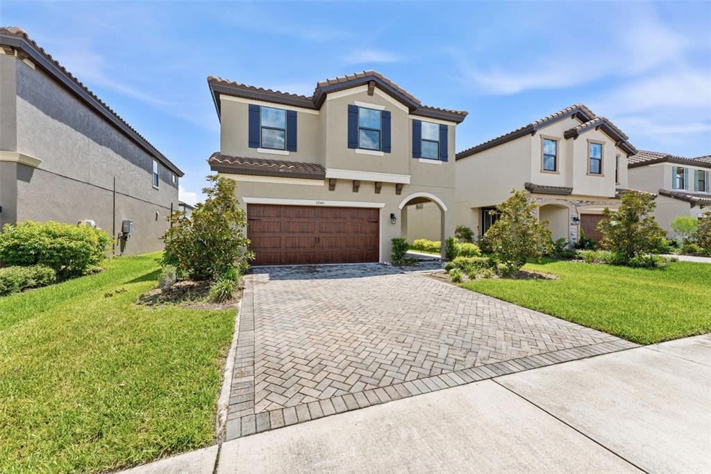 A two-story suburban house features a tan stucco exterior, dark shutters, and a paved driveway — 3940 MAURICE AVENUE, ODESSA, FL