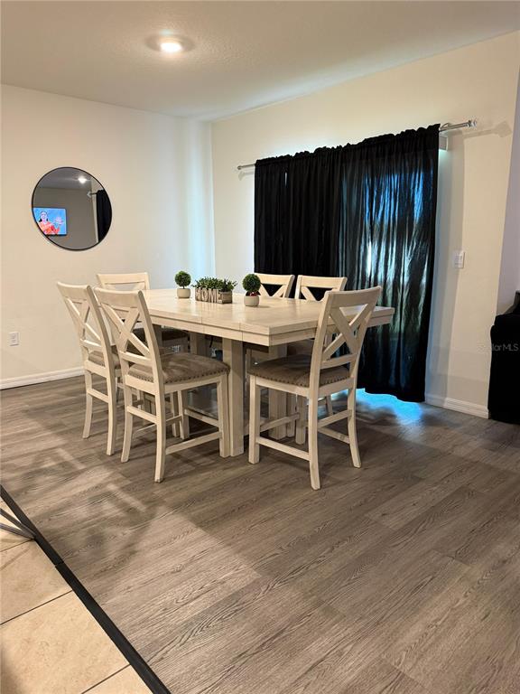 A dining room features a light-colored table with six chairs and dark curtains — 784 SILVER PALM DRIVE, HAINES CITY, FL