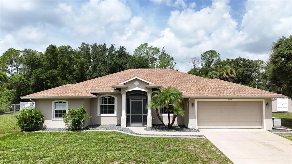 A single-story house with a tan stucco exterior, a shingled roof, and a two-car garage — 2613 TRIANNA STREET, NORTH PORT, FL