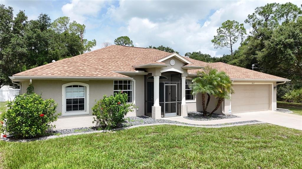 A single-story house with a tan exterior, brown shingled roof, and a screened front entryway — 2613 TRIANNA STREET, NORTH PORT, FL