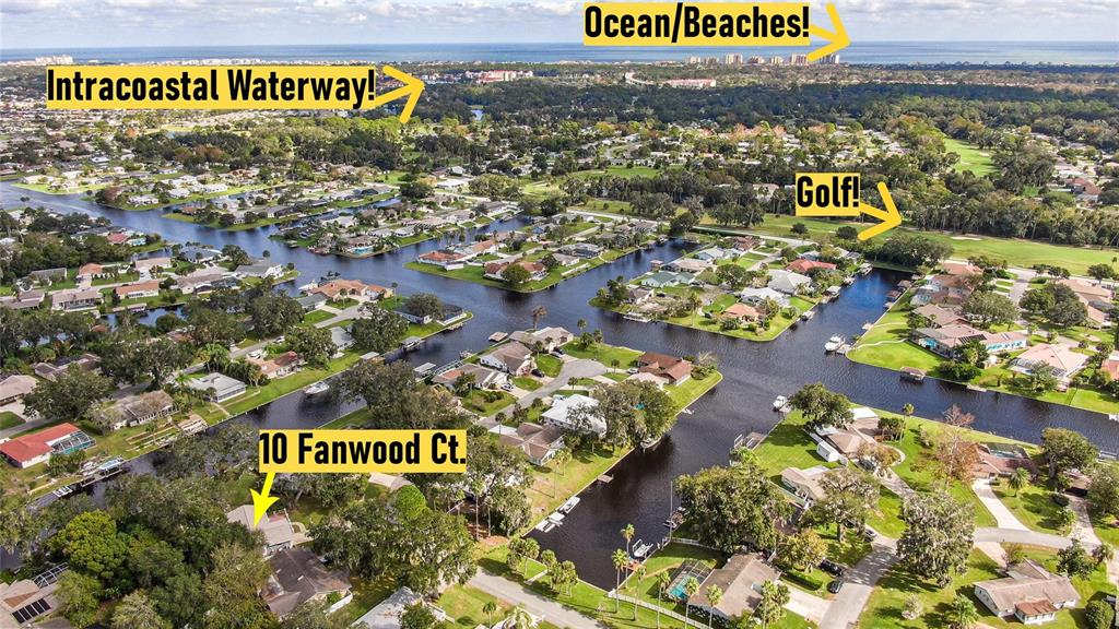 An aerial view shows a residential neighborhood with canals, surrounding greenery, and distant coastal water — 10 FANWOOD COURT, PALM COAST, FL