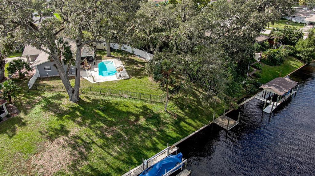 An aerial view of a backyard featuring a swimming pool, lawn, and private boat dock — 10 FANWOOD COURT, PALM COAST, FL