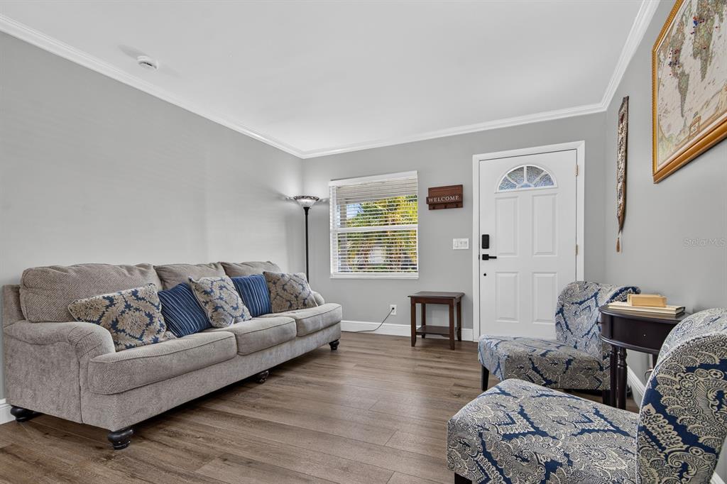 A living room features gray walls, wood-look flooring, a sofa, and two patterned armchairs — 4014 W LAND AVENUE, TAMPA, FL
