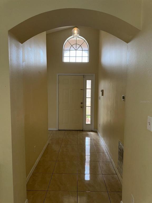 An entryway features a tiled floor, an arched ceiling, and a front door with sidelights — 11941 HATCHER CIRCLE, ORLANDO, FL
