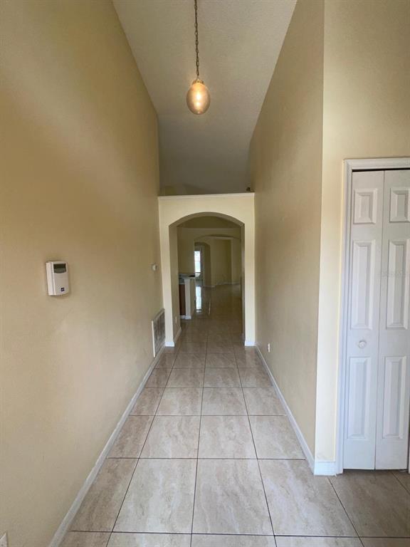 A hallway with beige walls, tiled floors, and an arched entryway leads to another room — 11941 HATCHER CIRCLE, ORLANDO, FL