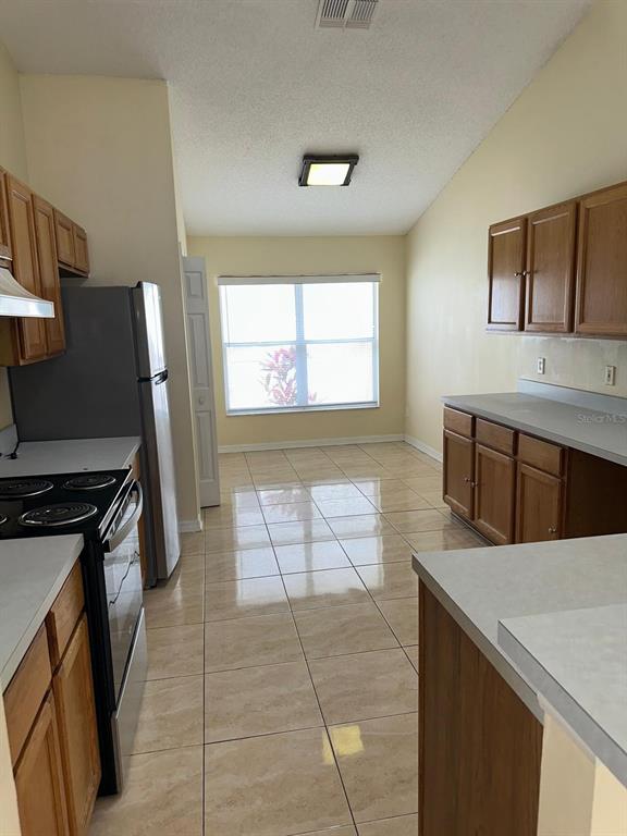 A kitchen with light tile floors, wood cabinets, and a stainless steel refrigerator — 11941 HATCHER CIRCLE, ORLANDO, FL