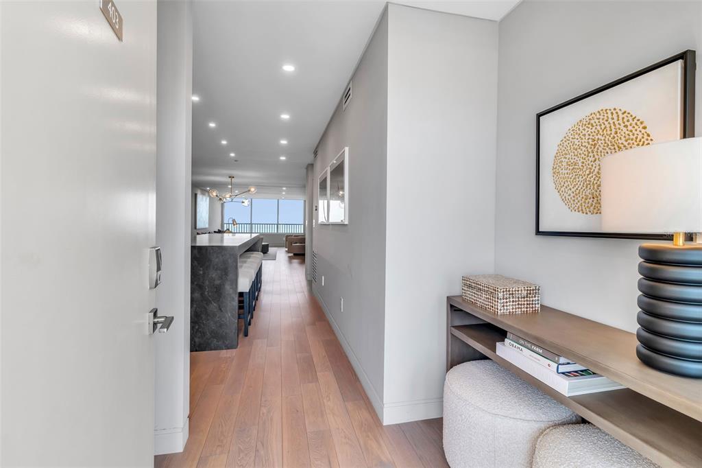 A view from an entryway into a modern apartment with wood floors and a kitchen island — 5740 MIDNIGHT PASS ROAD UNIT 403, SARASOTA, FL