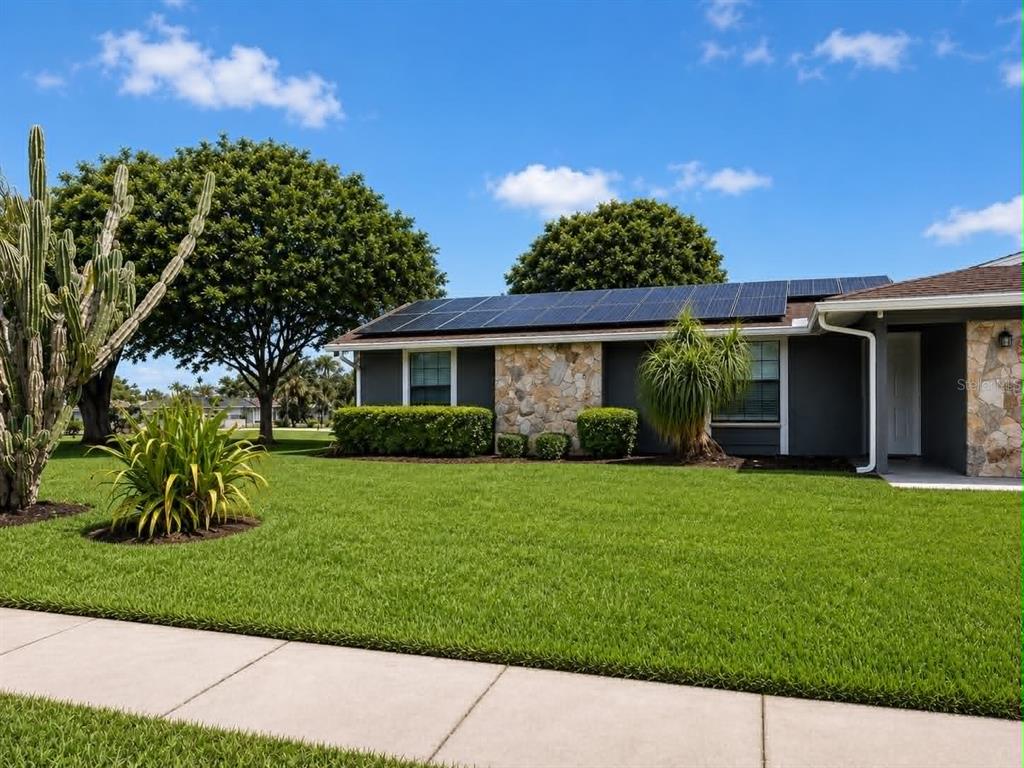 A single-story house with solar panels, stone accents, and a large front lawn — 3115 LOCKWOOD MEADOWS BOULEVARD, SARASOTA, FL