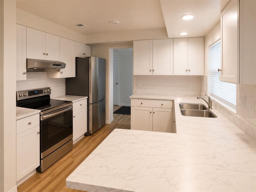 A kitchen features white cabinets, stainless steel appliances, and white marble-patterned countertops — 3115 LOCKWOOD MEADOWS BOULEVARD, SARASOTA, FL