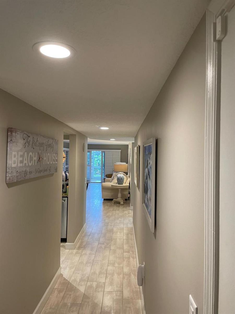 A hallway with light tile flooring leads to a living area with a glass door — 10980 S Ocean Drive # 111, Jensen Beach FL 34957, JENSEN BEACH, FL