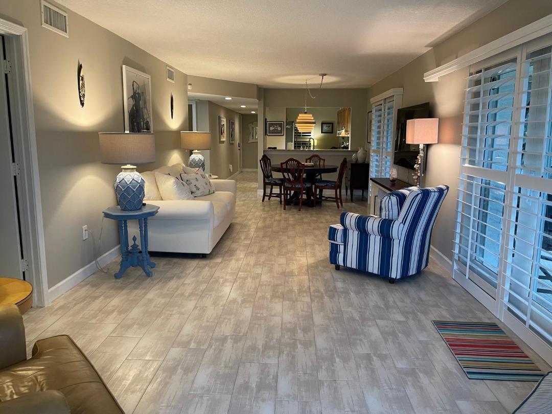 A living room with light tile floors, a white sofa, and a blue striped armchair — 10980 S Ocean Drive # 111, Jensen Beach FL 34957, JENSEN BEACH, FL